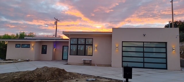Modern beige house with a glass garage door at sunset