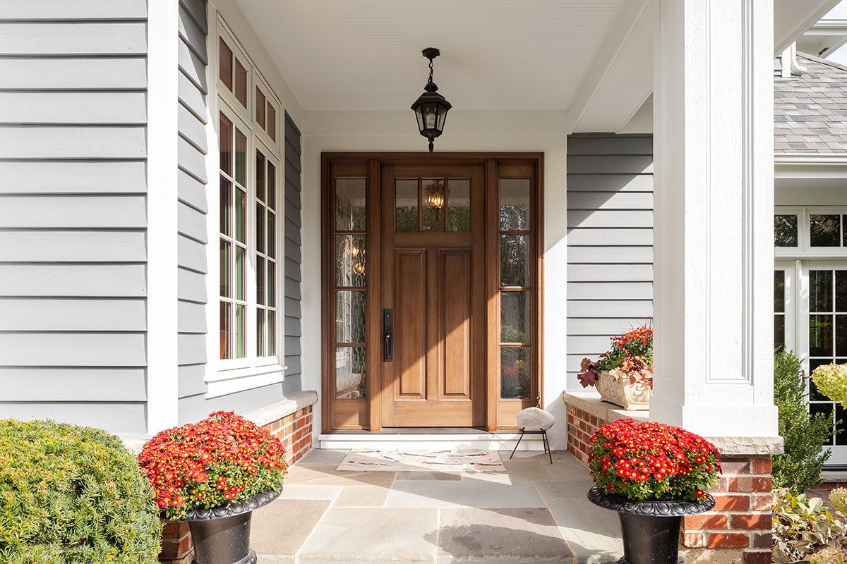 Wooden front door and windows on a gray-sided covered porch