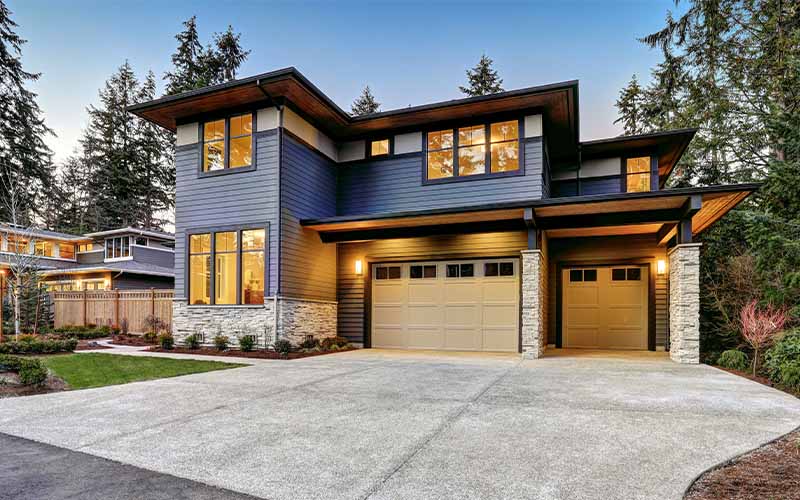 Large two-story house with blue siding, stone facade, and two garages.
