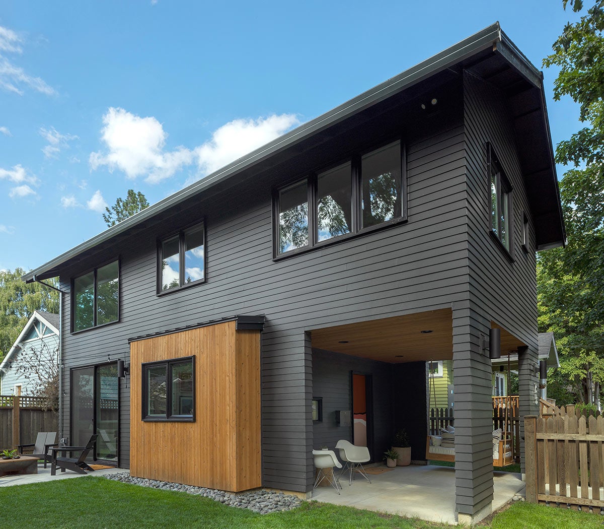 Modern dark gray house with wood accent and covered outdoor area