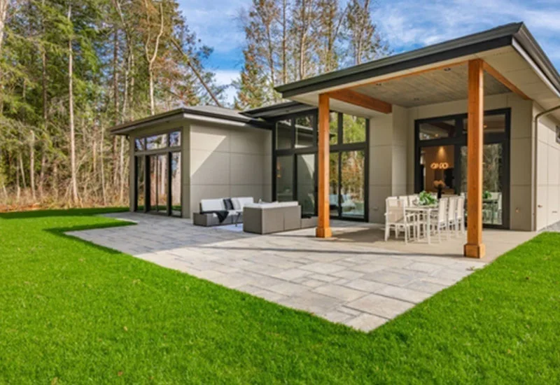 Modern house with patio, outdoor furniture, and surrounding forest