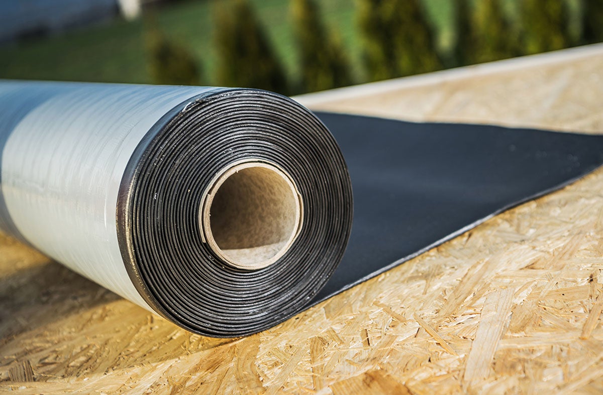 Close-up of black roofing underlayment roll on plywood sheathing